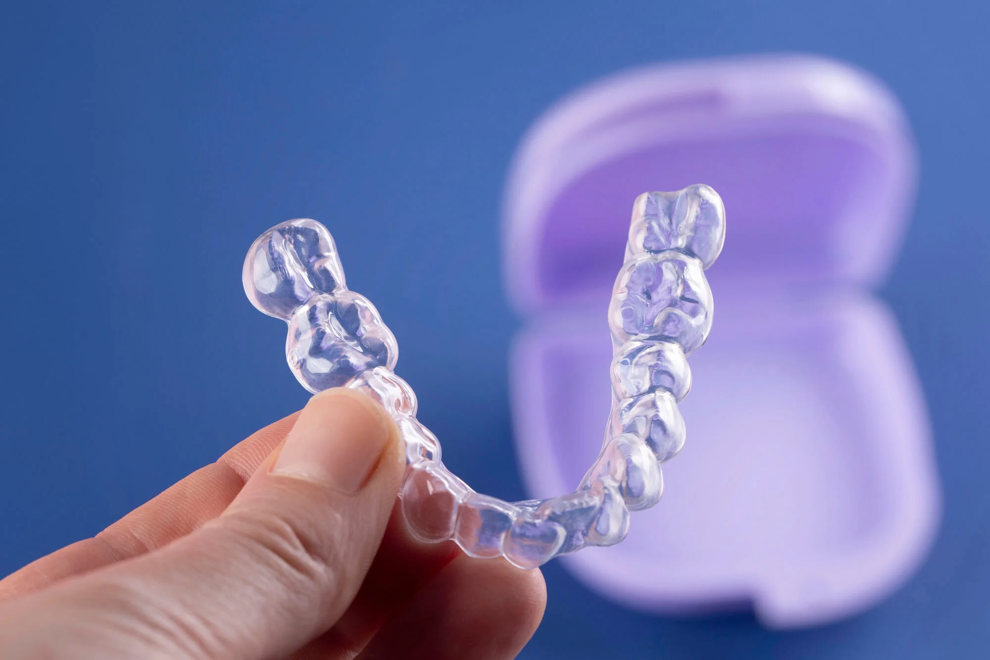 Invisalign treatment in Springfield, PA with blue backgroud and purple case.