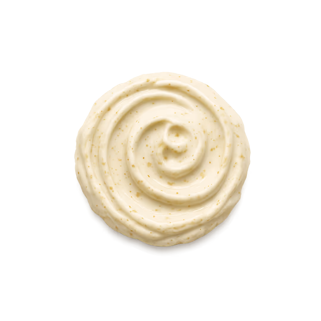 Swirl of creamy garlic sauce with small seasoning specks on a white background.