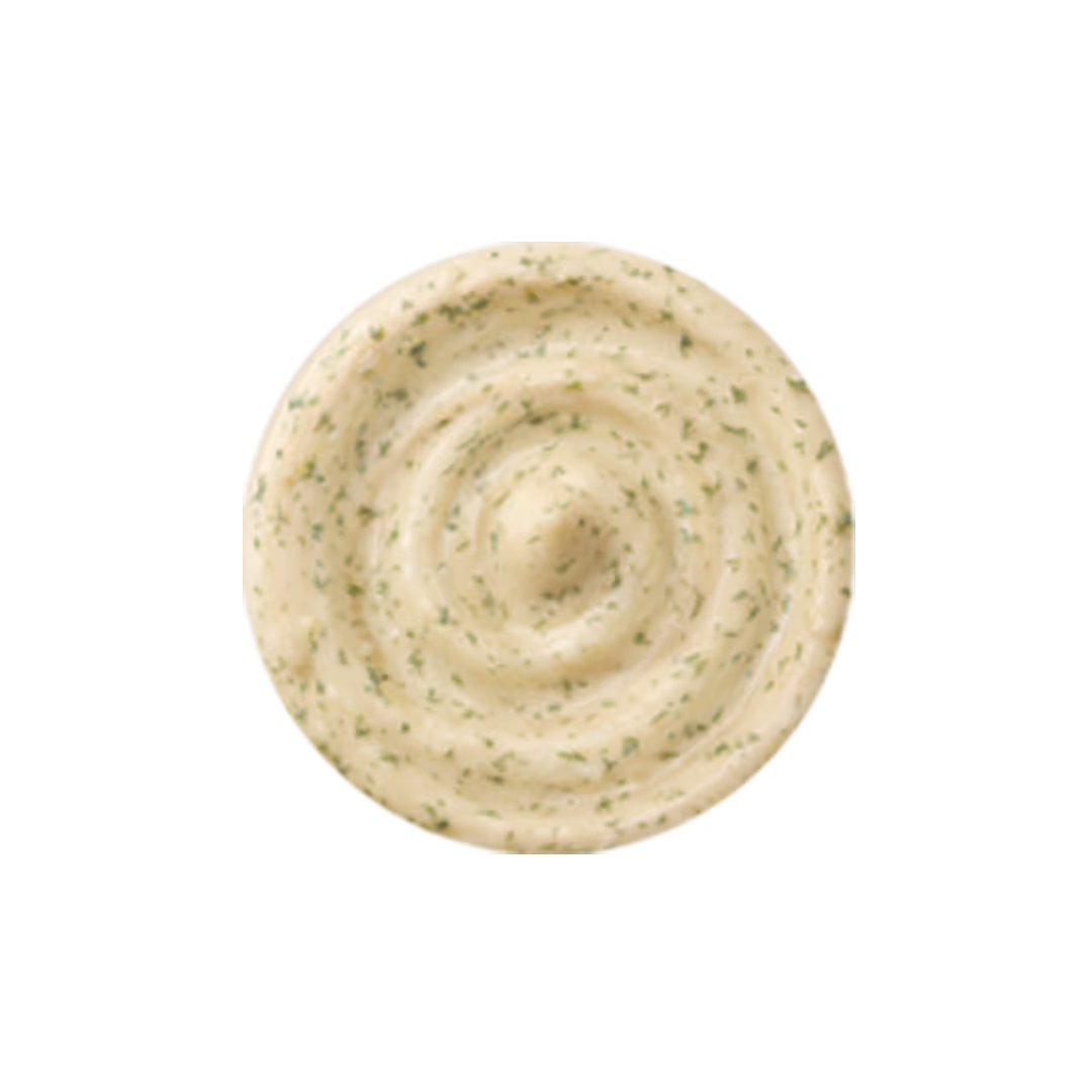 Swirl of creamy dill garlic sauce with green herb specks on white background.