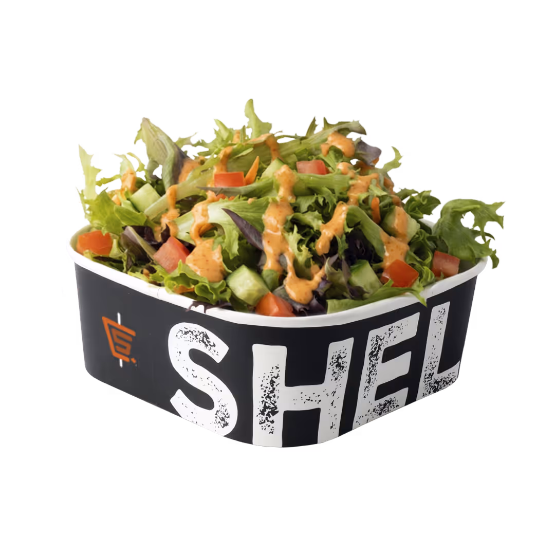 Mixed green salad with diced tomatoes and cucumbers topped with a creamy dressing in a black container labeled 'SHELF'.