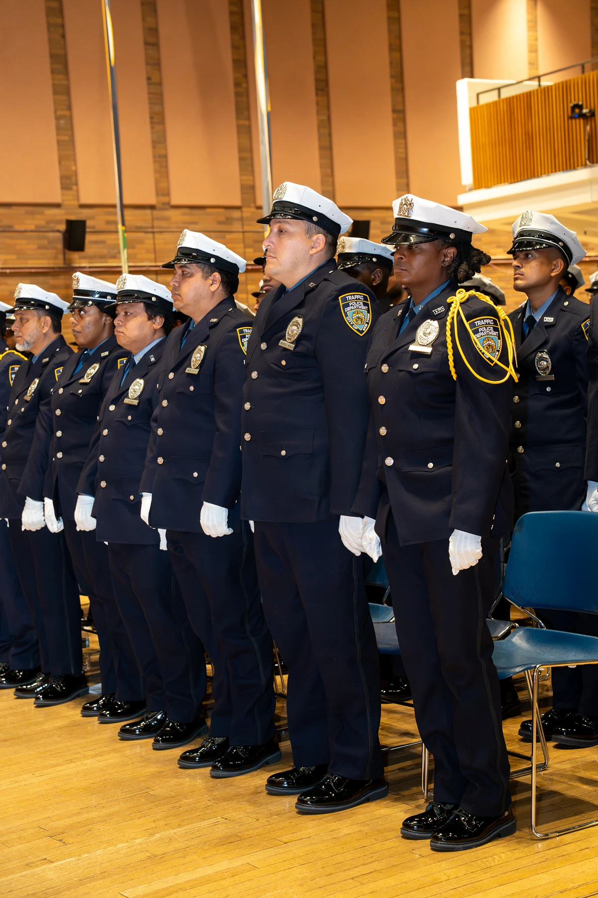 A line of Traffic Police Department officers standing in formal uniform indoors during a ceremony.