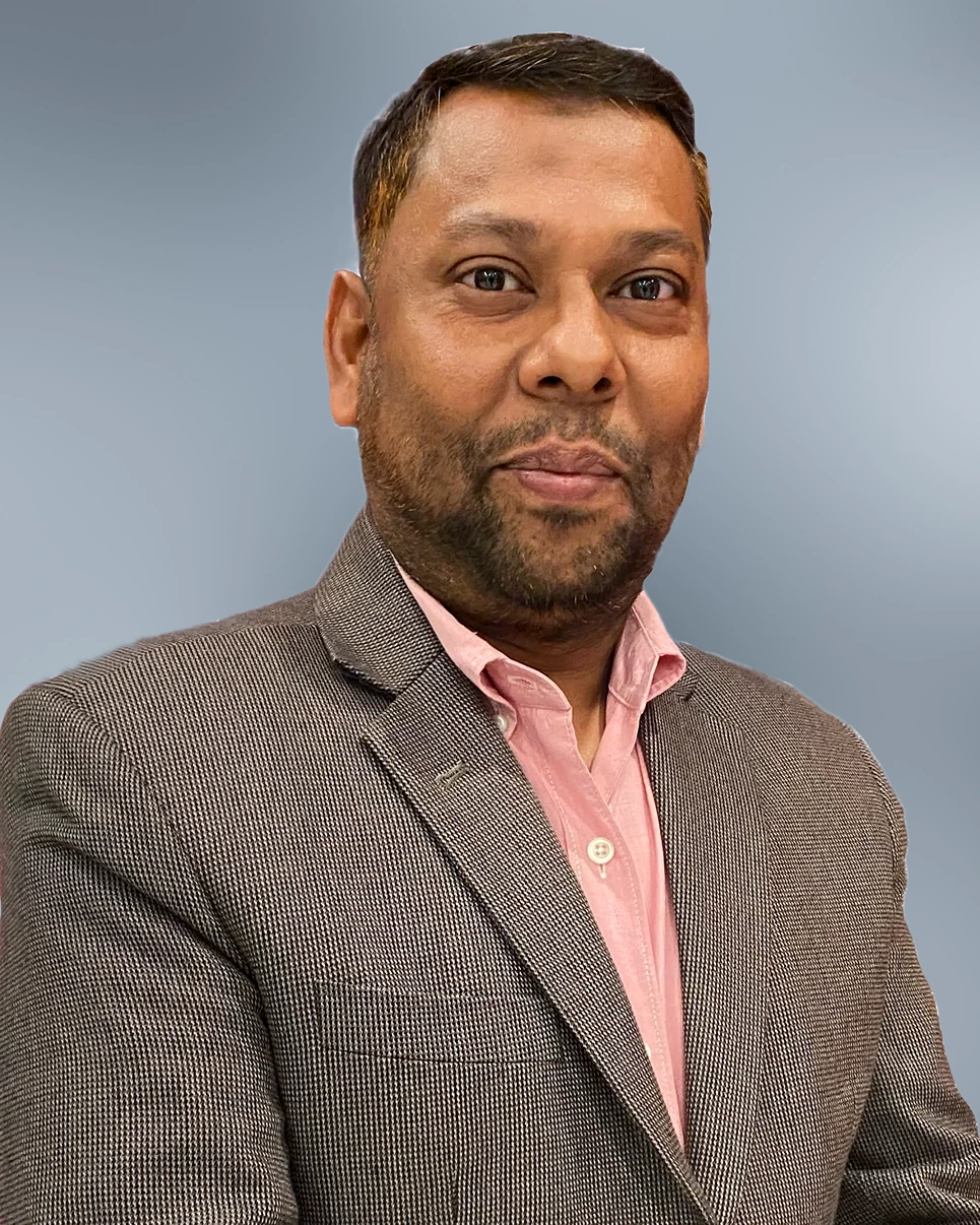 Portrait of a man wearing a brown textured blazer and a light pink shirt against a gradient blue-gray background.