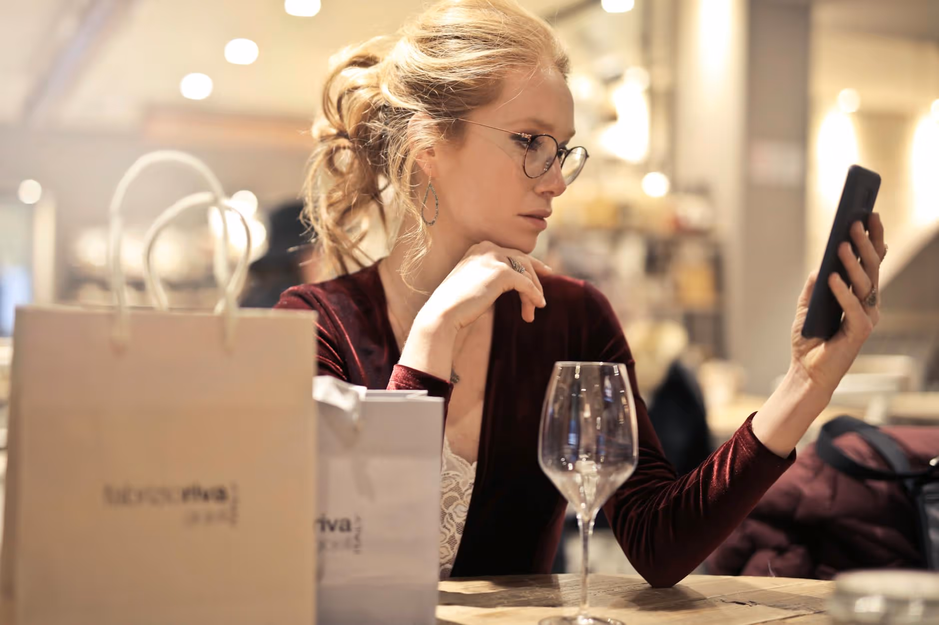 Elegant woman checking wine options on her phone at a restaurant