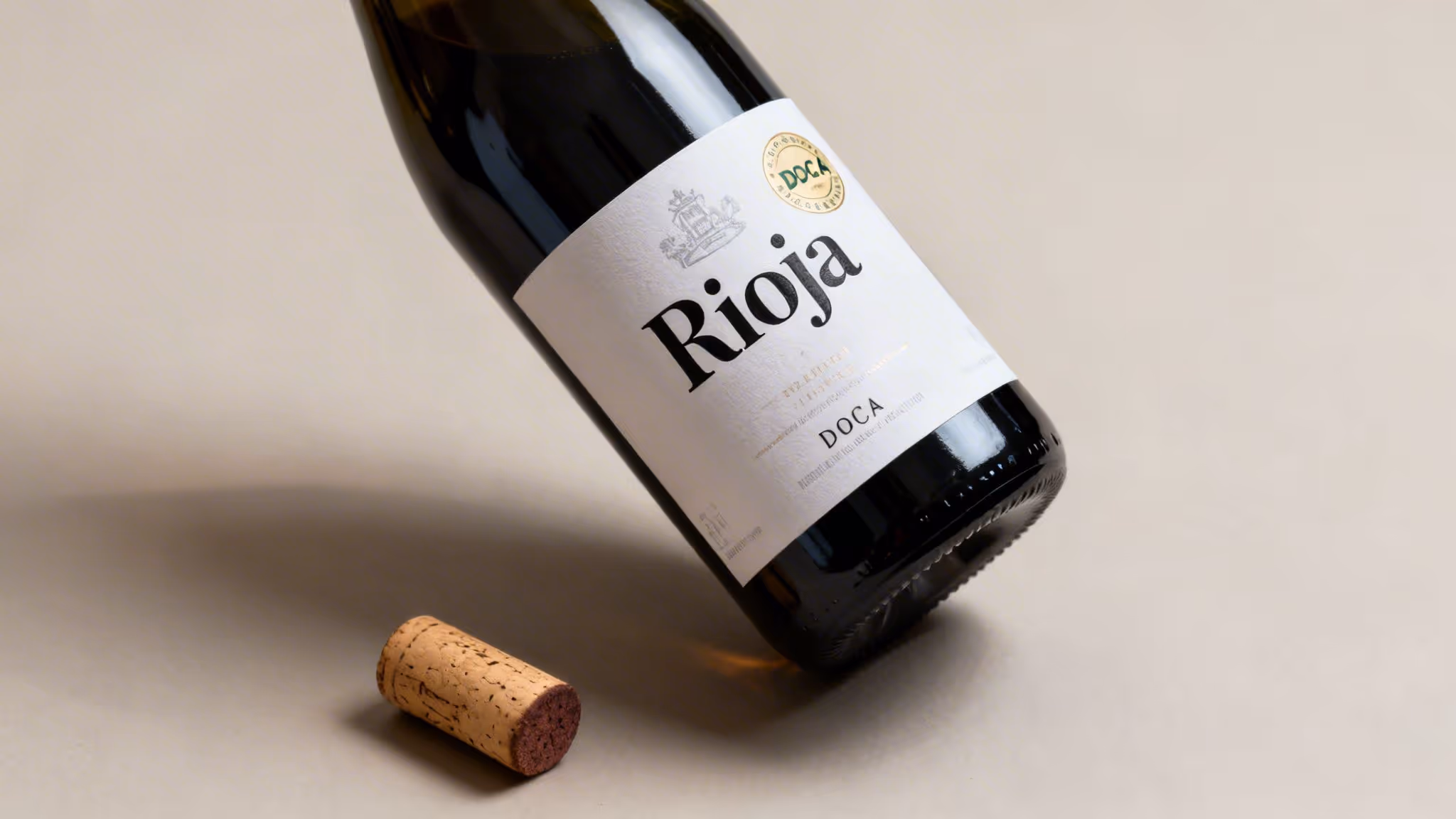 A dark wine bottle with a white 'Rioja' label and a cork on a light gray surface.