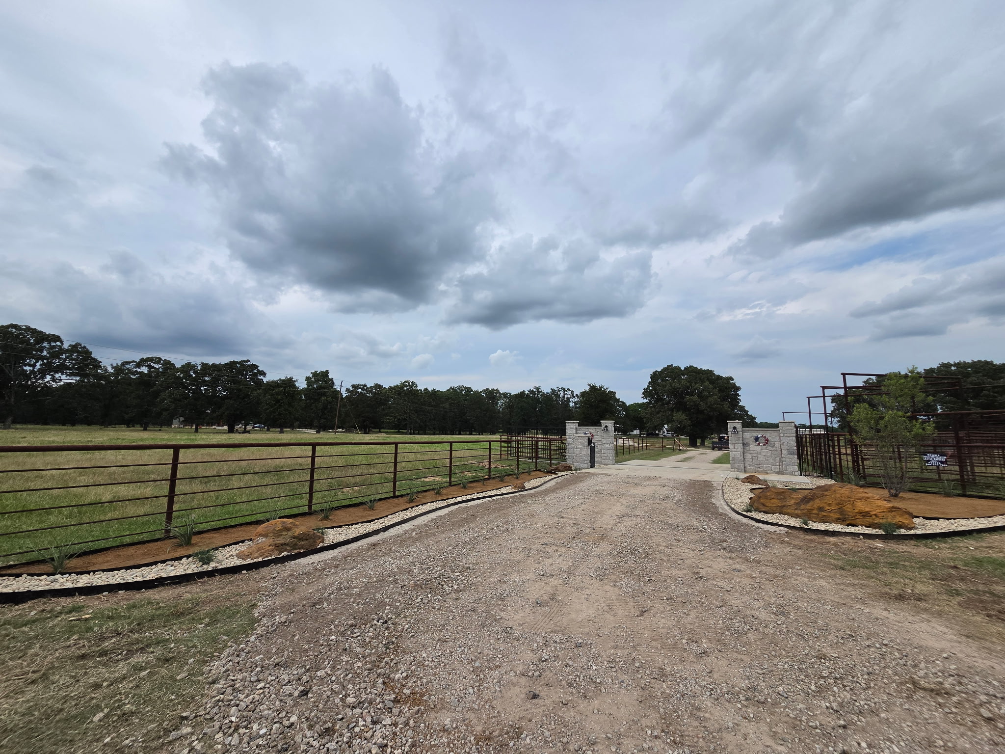 East Texas acreage entrance landscaped with stone, river rock, planting beds and large natural boulders