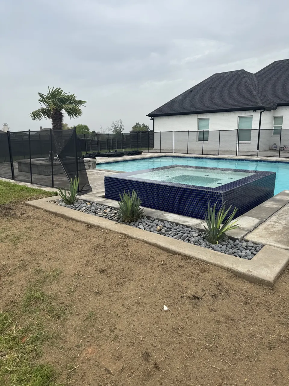 Concrete landscape border with Mexican beach pebbles and Adam’s needle in Canton