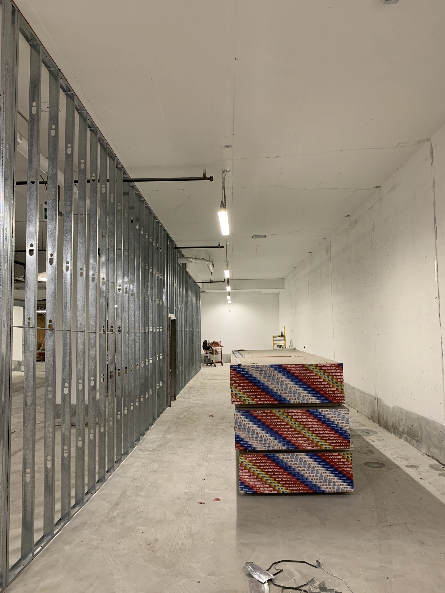 Stacks of drywall sheets on the right side of the metal wall studs installed.
