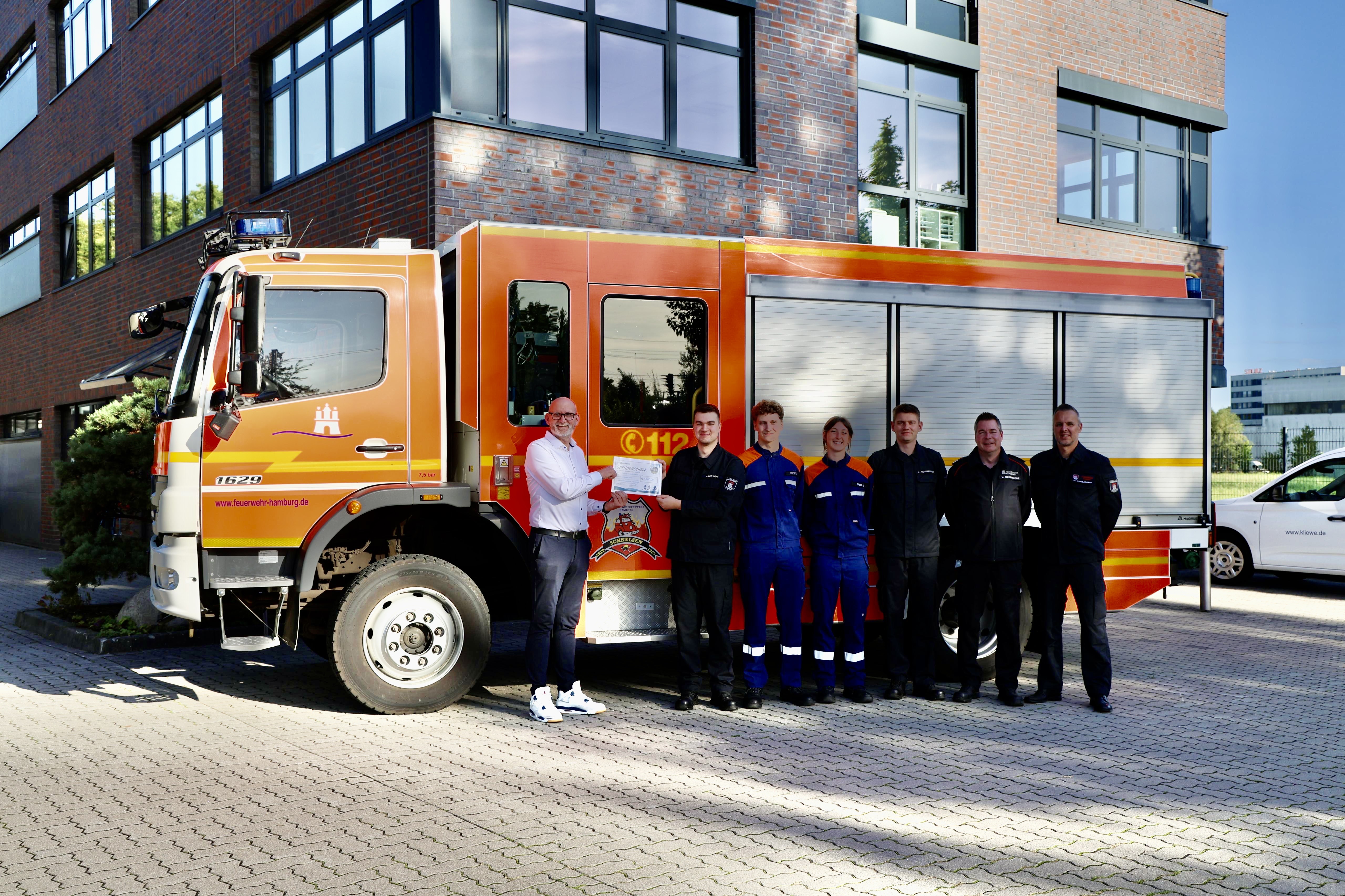 Thomas Kliewe übergibt den Spendenscheck an die Vertreter der Feuerwehr Schnelsen.