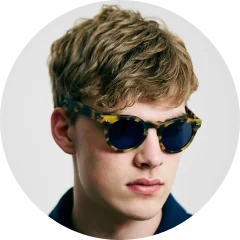 A young man wearing sunglasses and a blue shirt.