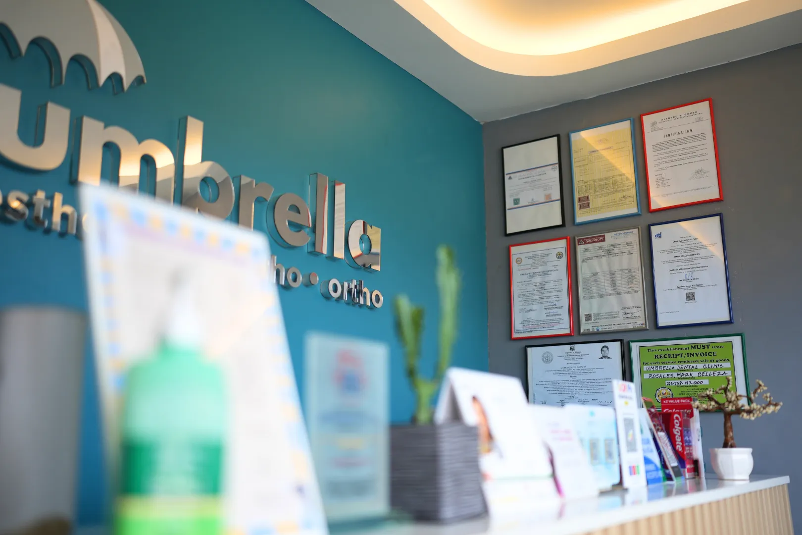 Umbrella Dental Clinic counter decorated with gold and green Christmas ornaments, displaying a dental services pricelist and a Christmas promo sign offering 20% off prostho cases until December 23, 2025.