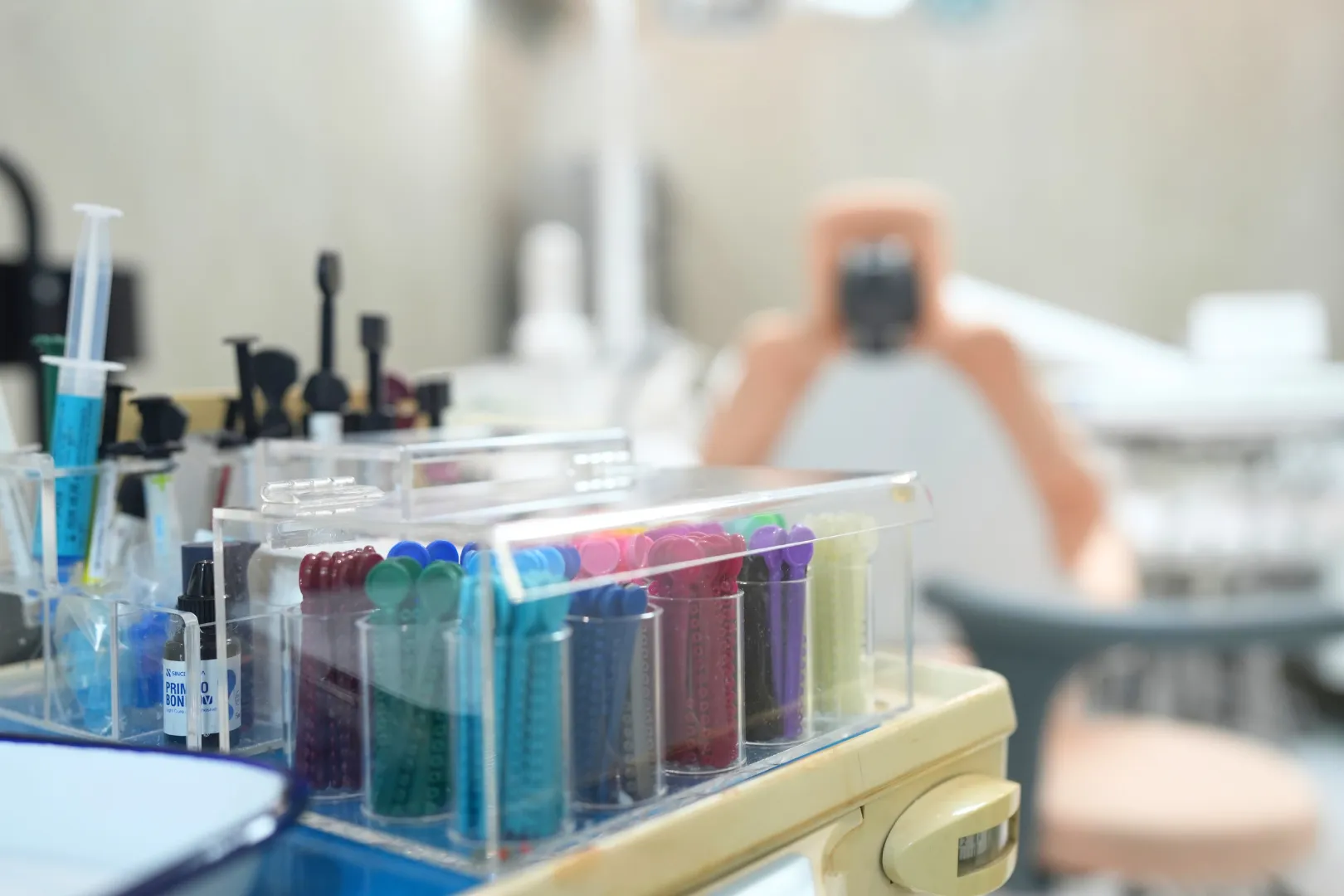Modern dental clinic with two dental chairs and overhead dental lights in rooms with gray walls and white tiled floors inside Umbrella Dental Clinic.