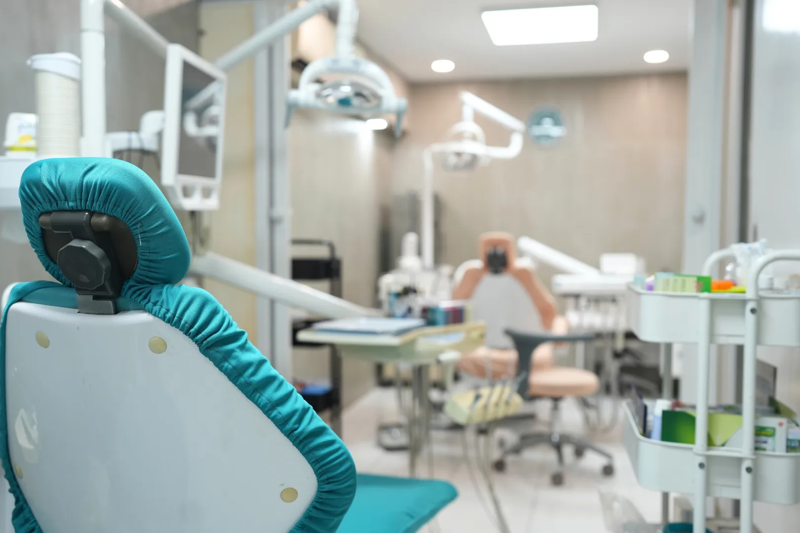 Reception desk of Umbrella Dental Clinic decorated with Christmas garlands and QR code display stands, Christmas tree with gold decorations, and a TV screen showing a festive fireplace scene.