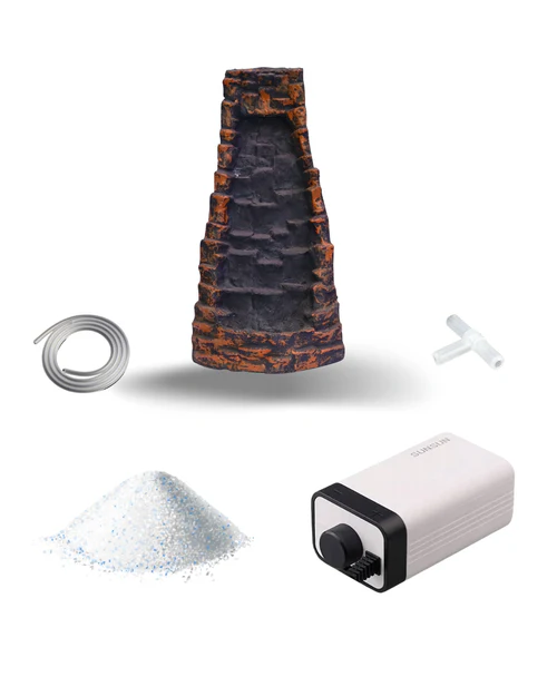 Aquarium decoration kit including a stone cave ornament, tubing, a T-shaped connector, white tank substrate, and a small white air pump with control knob.