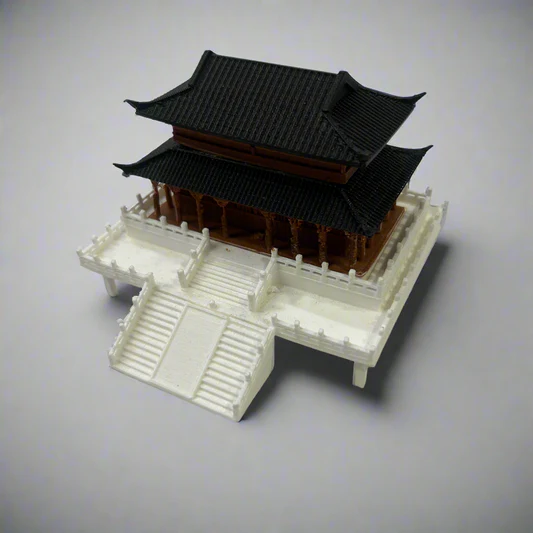 Miniature model of a traditional Asian-style building with a black curved roof, brown pillars, and white stone steps and railings.