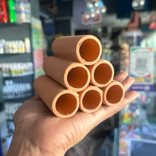 Hand holding six brown cylindrical tubes arranged in a pyramid shape inside a store.