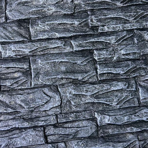 Close-up of textured gray stone wall with layered, irregular rectangular blocks.