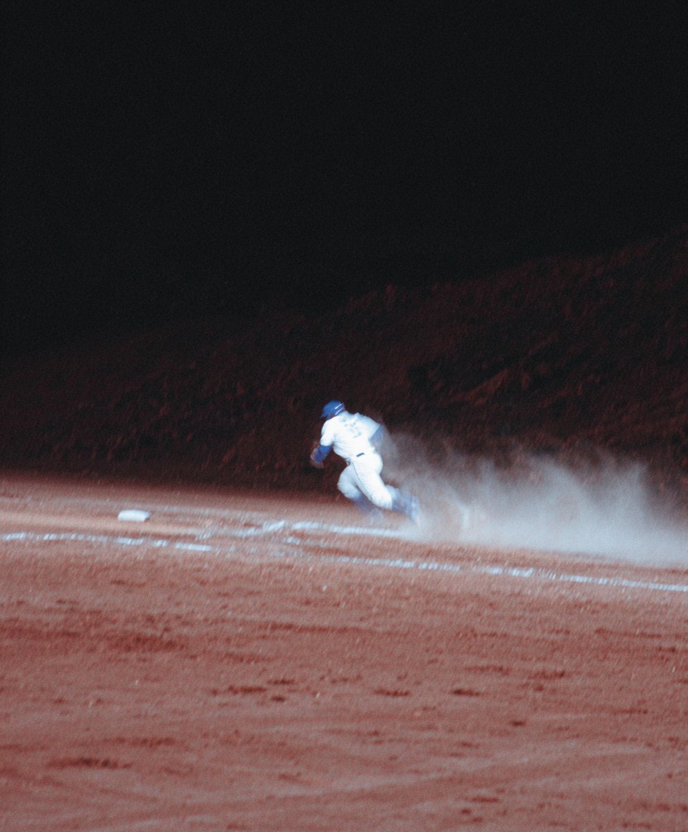 a lady with blonde curly hair using a computer in a office, we can see her coworkers in the background