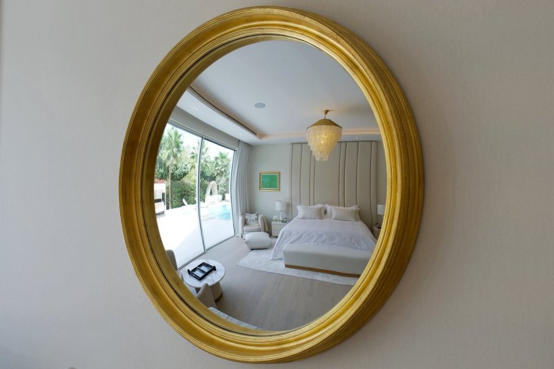 Round gold mirror reflecting luxury bedroom in Al Barari villa renovation Dubai