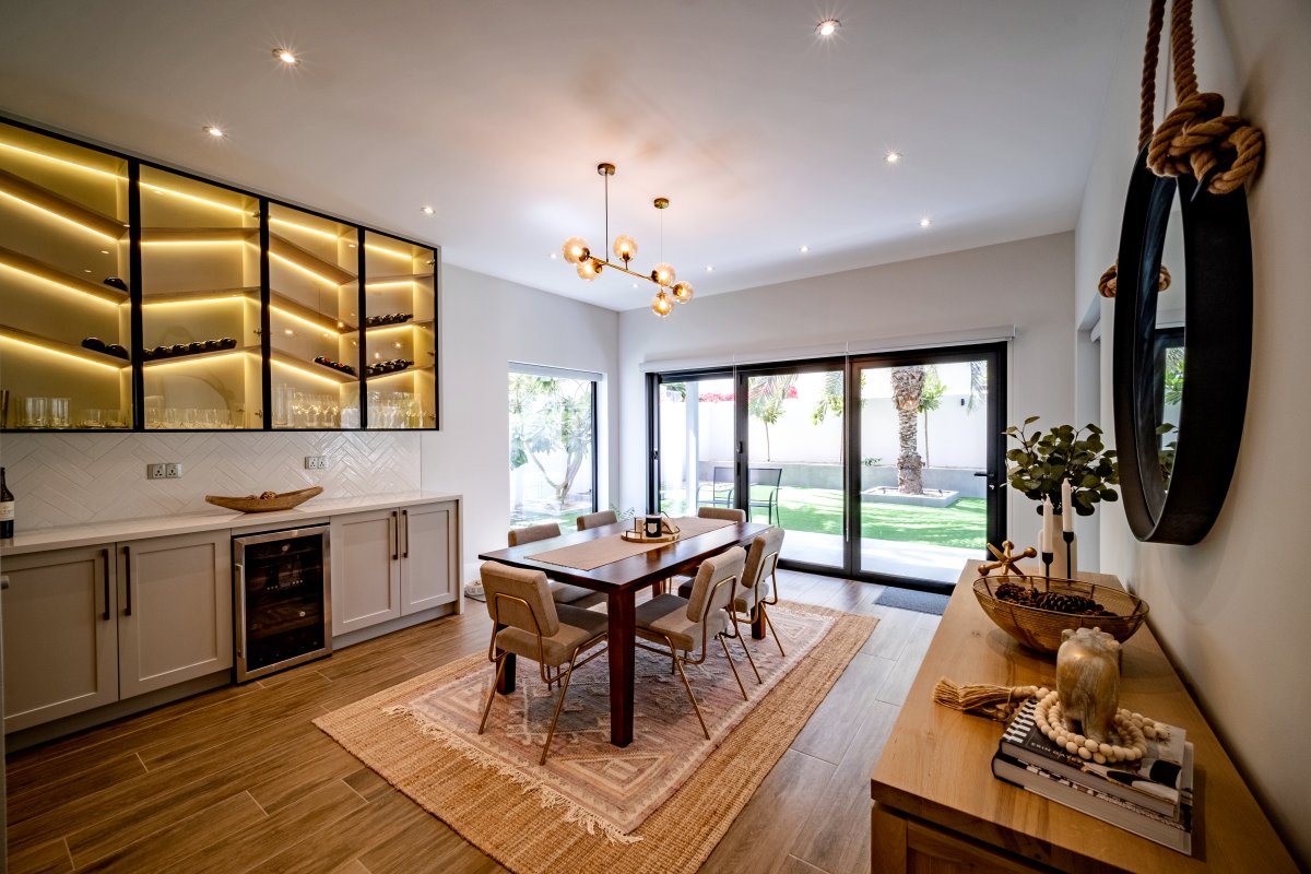 Modern dining room with illuminated wine display cabinet and garden views in renovated Meadows villa Dubai