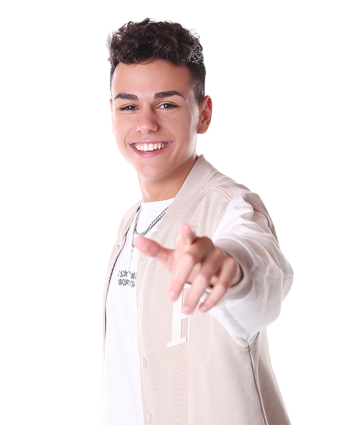 Junger Mann mit lockigem Haar lächelt und zeigt mit der Hand auf die Kamera vor weißem Hintergrund.