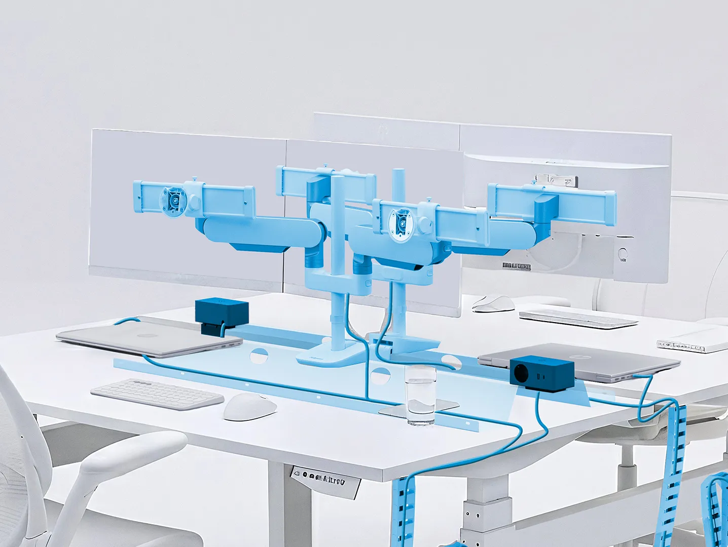 Bureau in een kantoor met dubbele monitorarmen, twee laptops, een draadloos toetsenbord en muis, en kabelbeheer in blauw.
