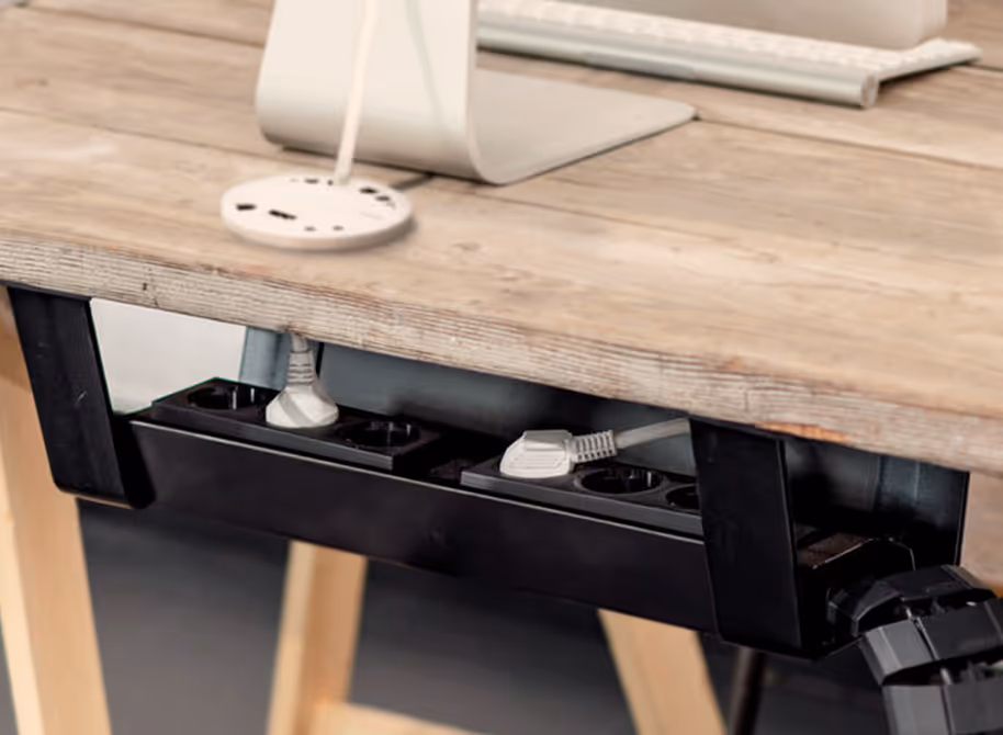 Stekkerdoos bevestigd onder een houten bureau, met twee stekkers aangesloten.