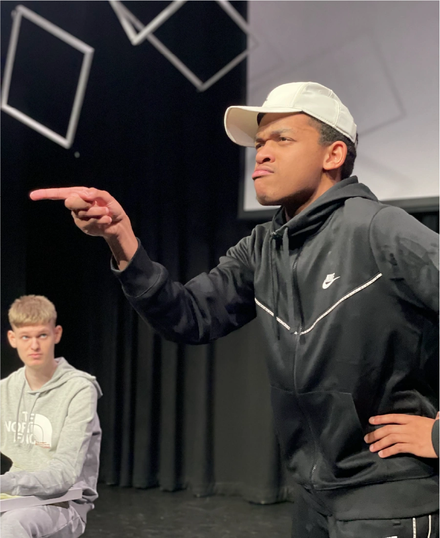 Woman wearing a grey hijab sorting black clothing in a clear plastic bin indoors.