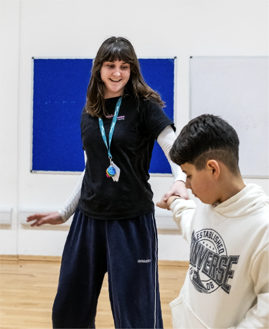 Woman wearing a grey hijab sorting black clothing in a clear plastic bin indoors.