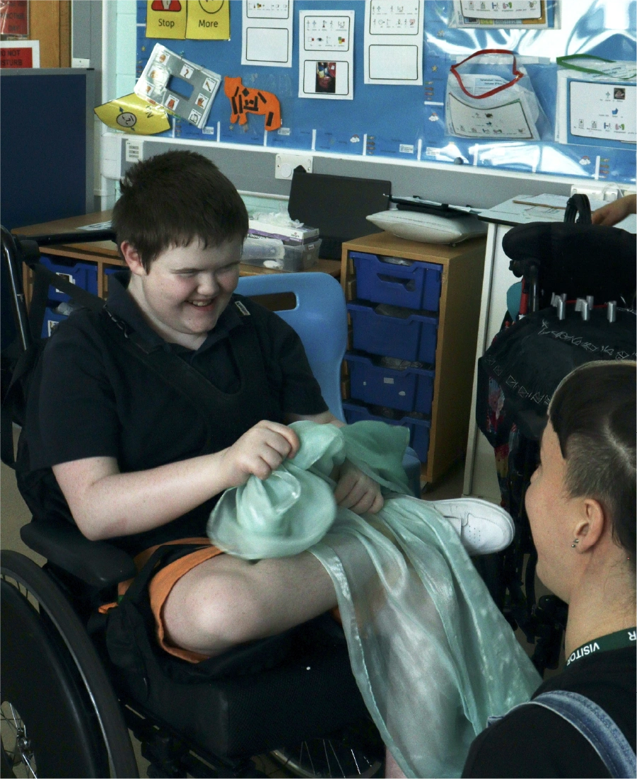 Woman wearing a grey hijab sorting black clothing in a clear plastic bin indoors.