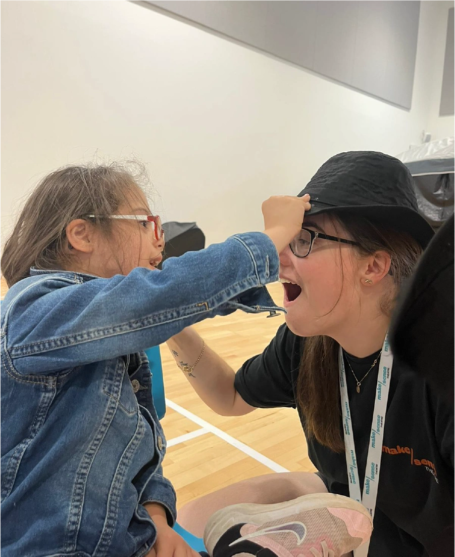 Woman wearing a grey hijab sorting black clothing in a clear plastic bin indoors.