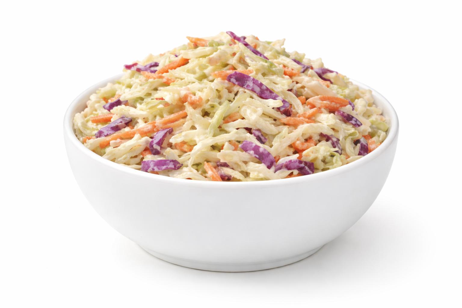 White bowl filled with coleslaw made of shredded cabbage, carrots, and purple cabbage in creamy dressing.