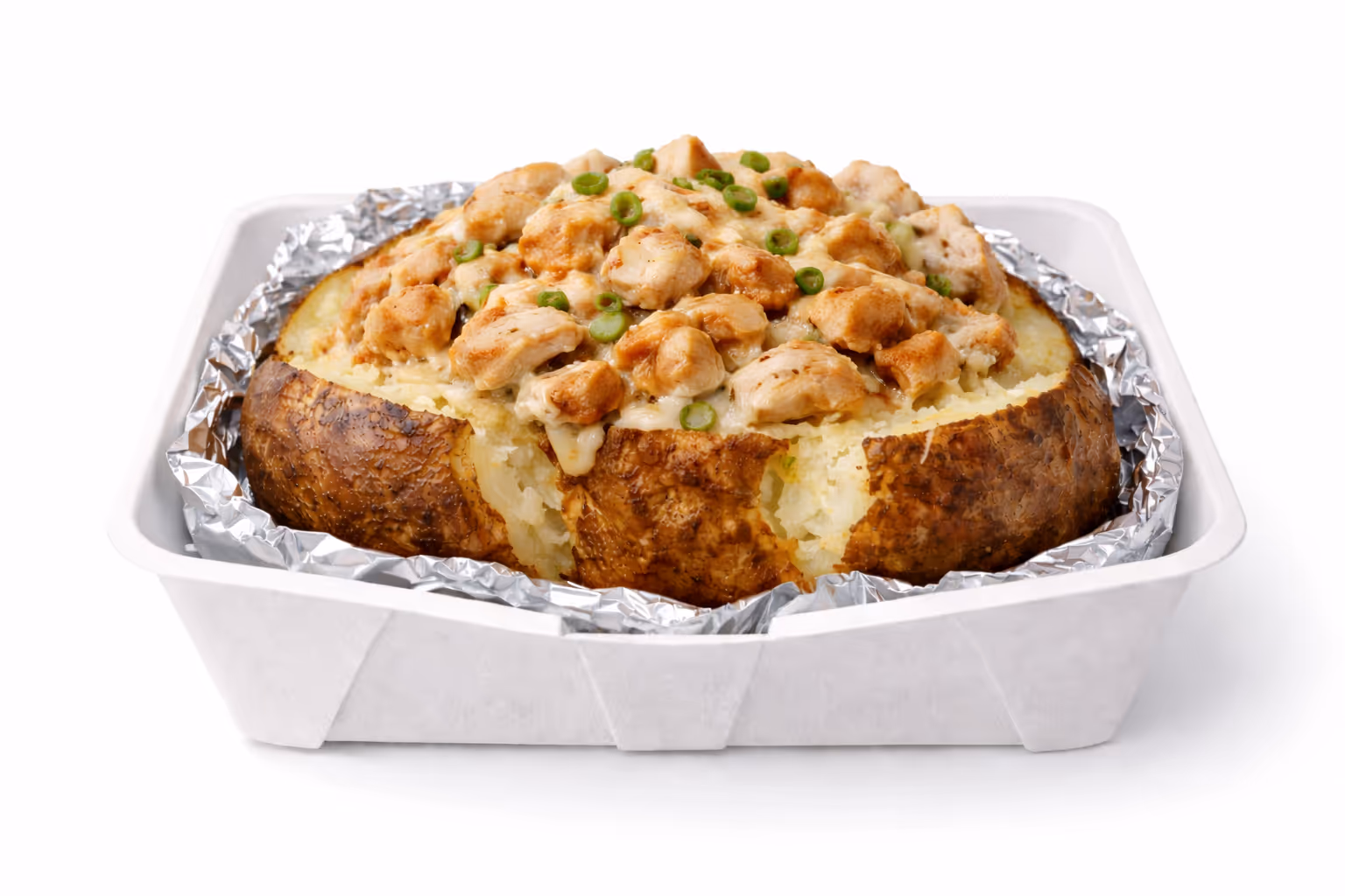 Baked jacket potato topped with chunks of cooked chicken, melted cheese, and sliced green onions in a foil-lined container.