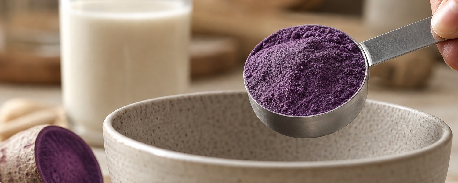 Cuillère doseuse remplie de poudre d’ube violette avec morceaux d’ube