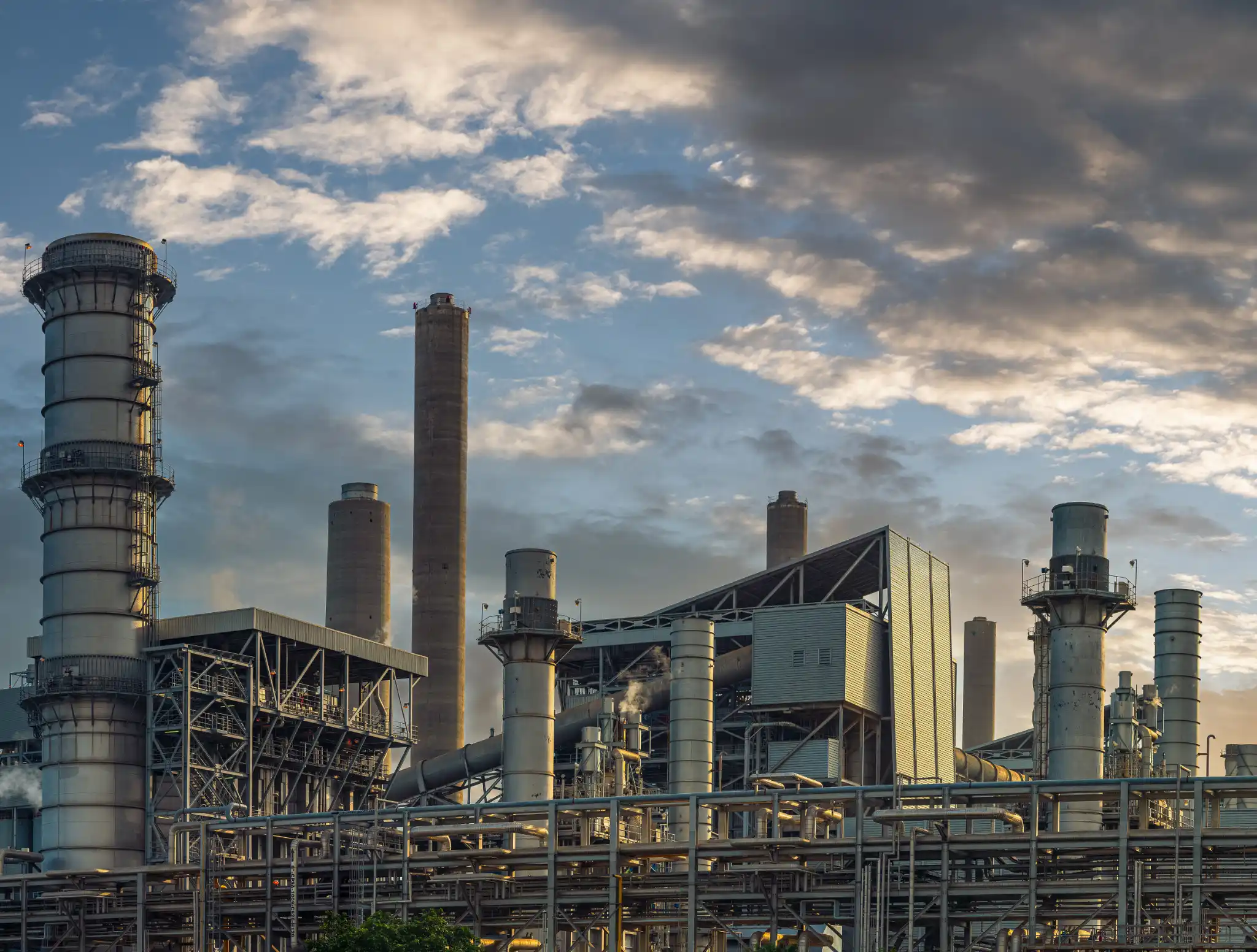 Large teal industrial generator with modernhiring.co.in label, positioned outdoors against a white wall and protected by yellow and black safety railing.
