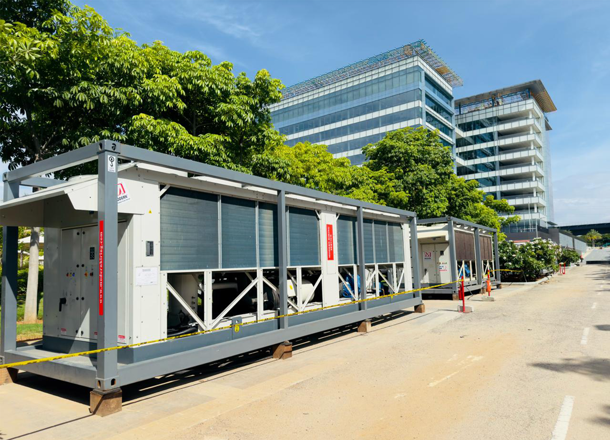 Industrial rooftop HVAC unit with exposed copper pipes and cooling fans under a cloudy sky.