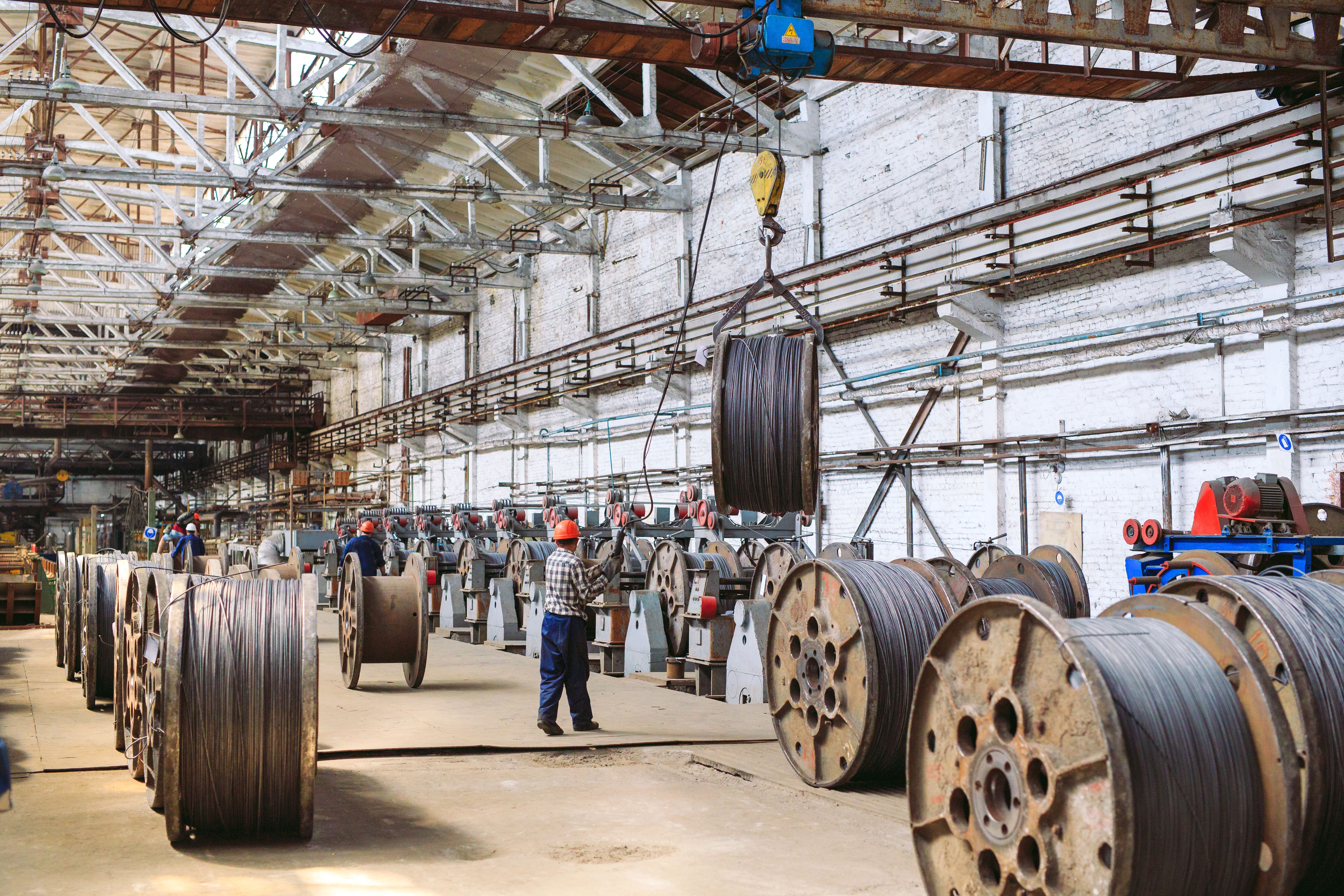 Large teal industrial generator with modernhiring.co.in label, positioned outdoors against a white wall and protected by yellow and black safety railing.