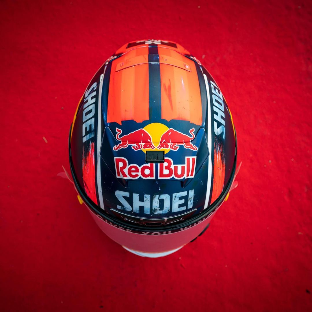 Top view of a motorcycle helmet with Red Bull and Shoei logos on a red background.