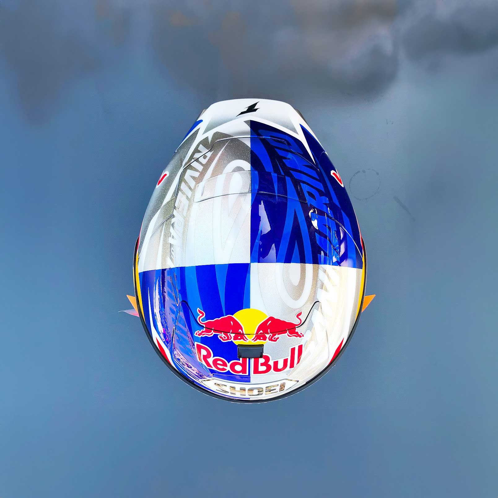Top view of a motorcycle helmet with Red Bull logo and Shoei branding on blue and white checkered design.