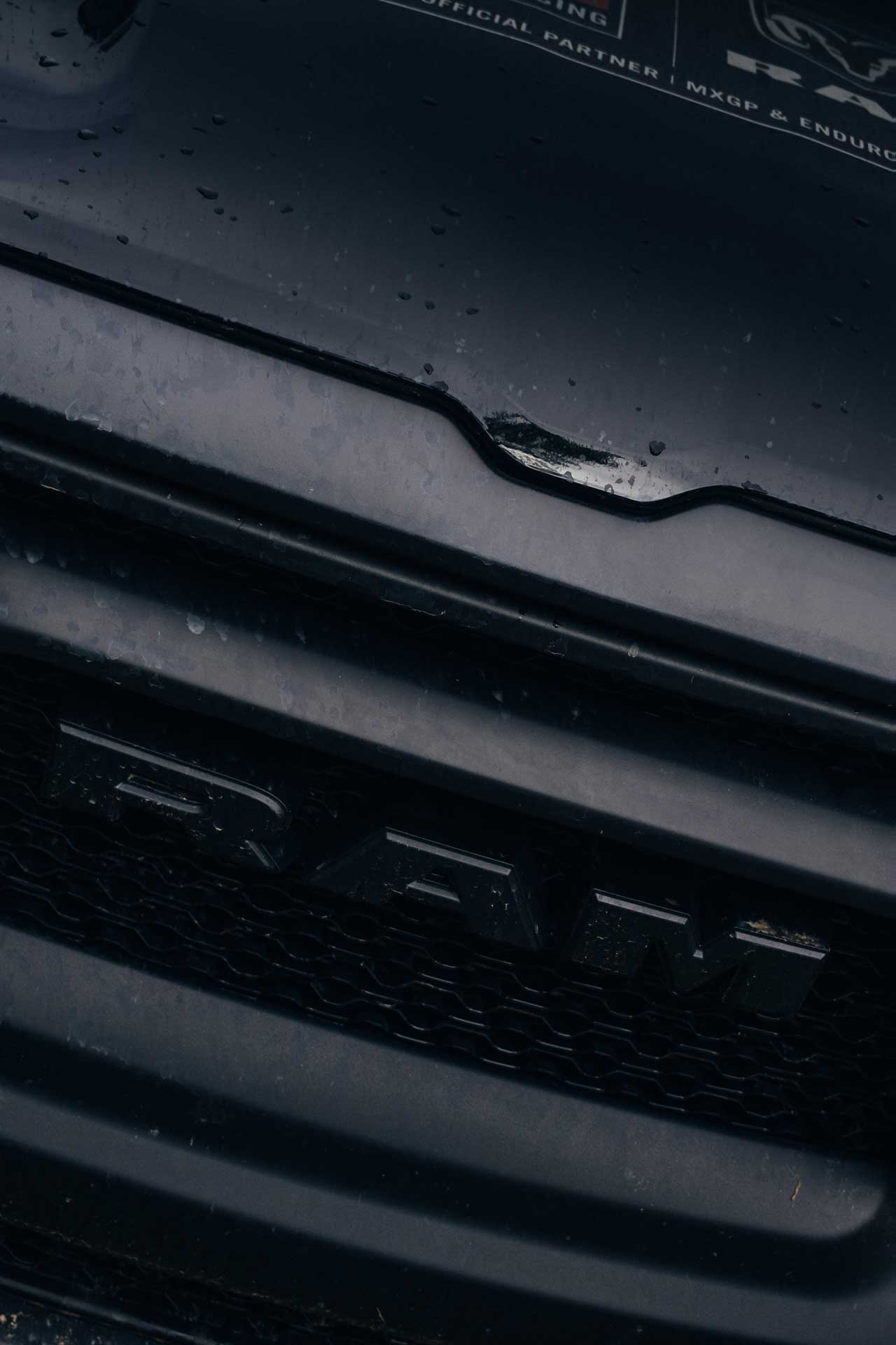 Close-up of the black RAM truck grille with water droplets on the surface.