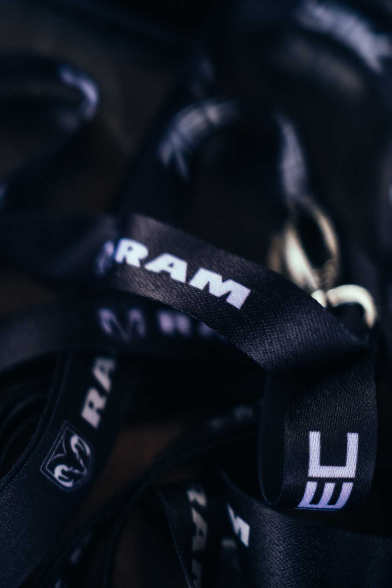 Close-up of black fabric straps with the white RAM logo printed on them.