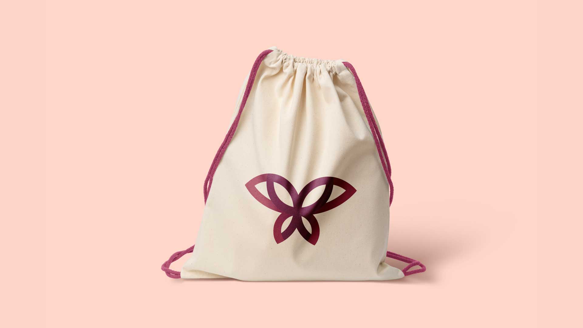 Beige drawstring bag with maroon intertwined butterfly-shaped logo and matching maroon drawstrings.