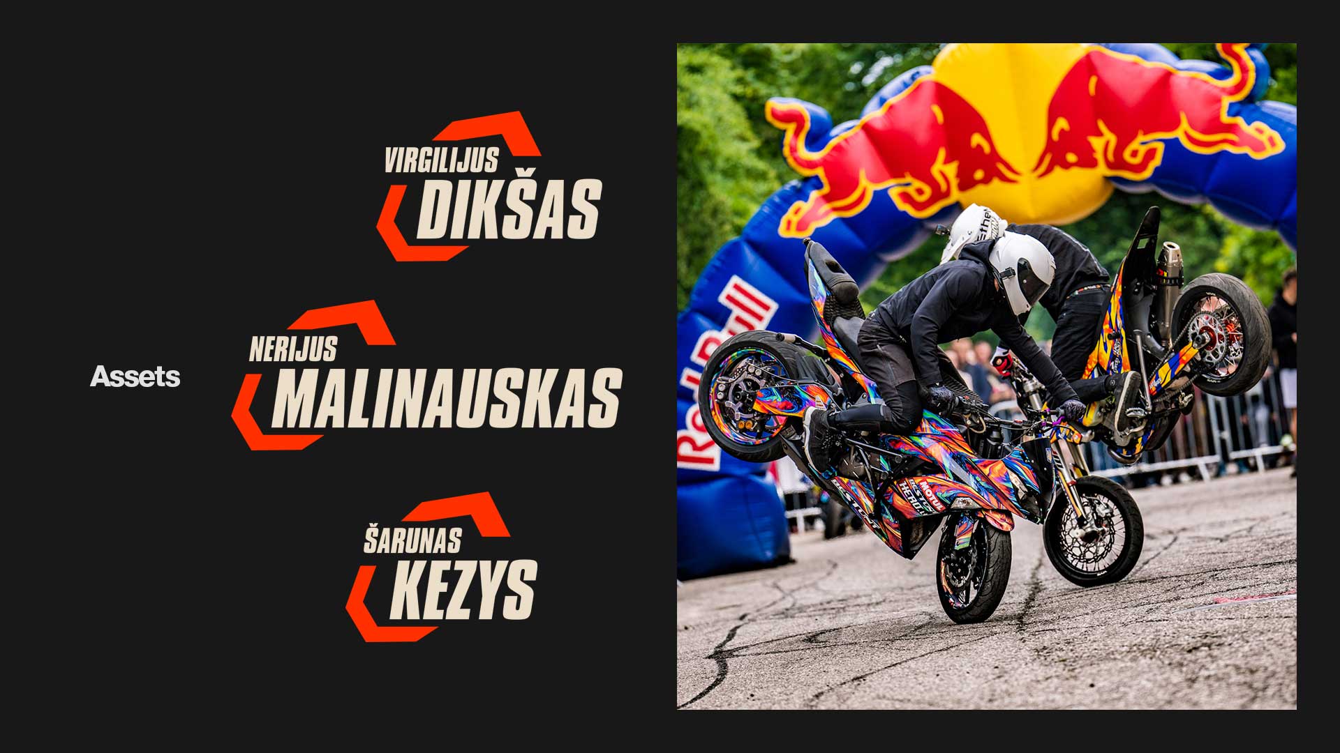 Two stunt riders in black gear and white helmets performing tricks on colorful motorcycles with a Red Bull inflatable arch in the background.