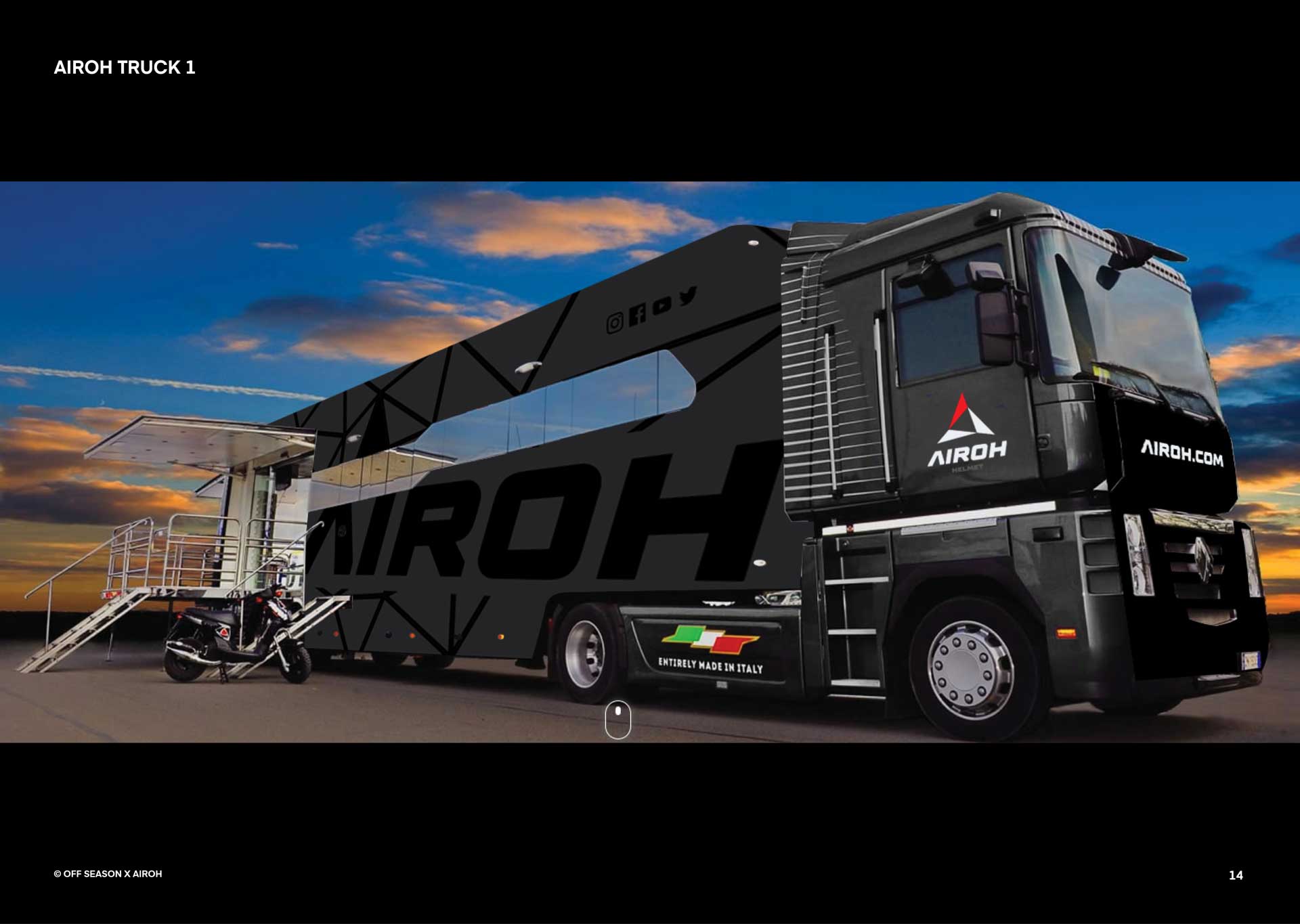 Black Airoh branded truck with an extended side platform, a motorcycle parked next to it, and a sunset sky in the background.