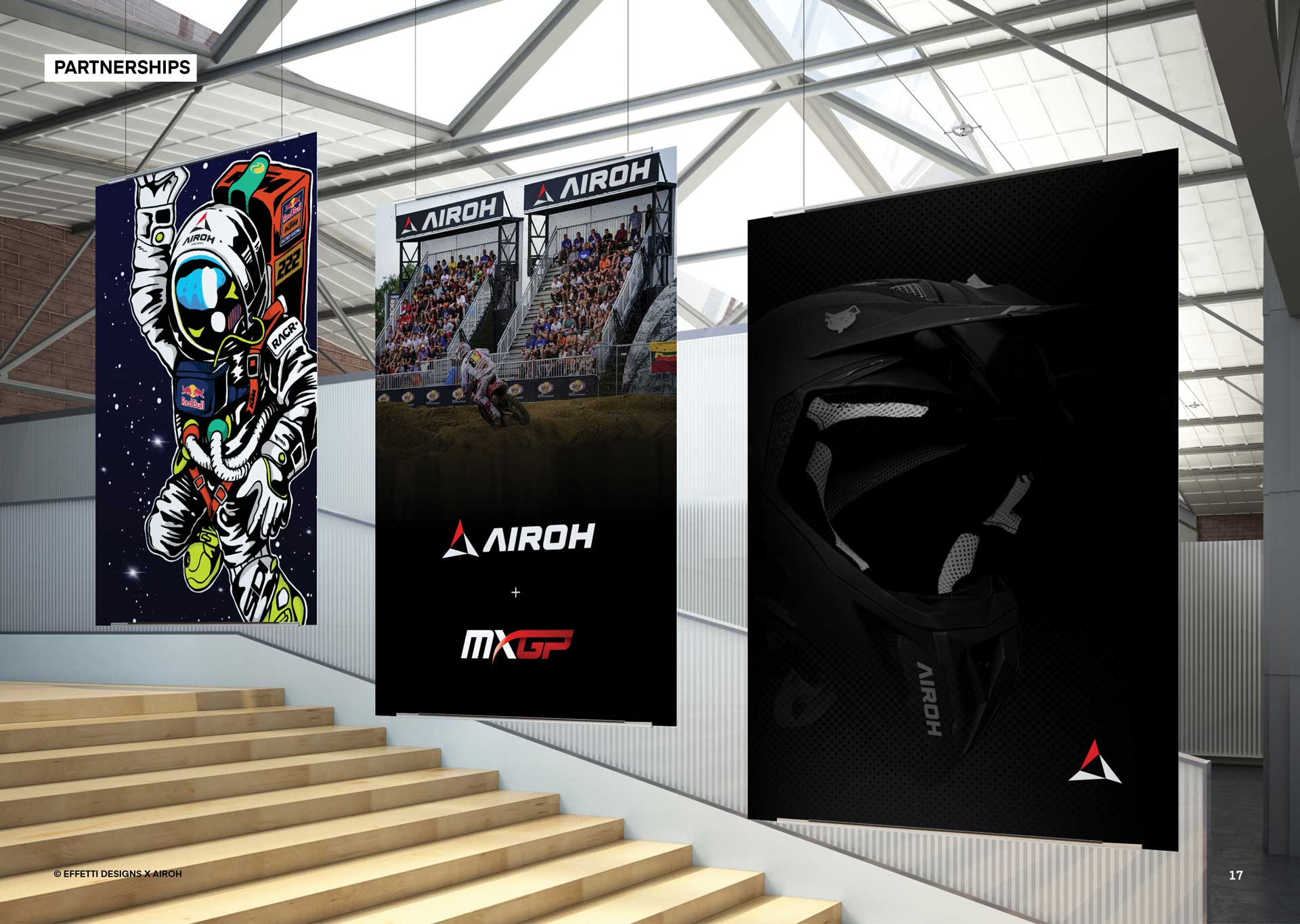 Three hanging banners featuring Airoh logos, a motocross race scene with audience, a black motocross helmet, and a cartoon astronaut in racing gear waving.
