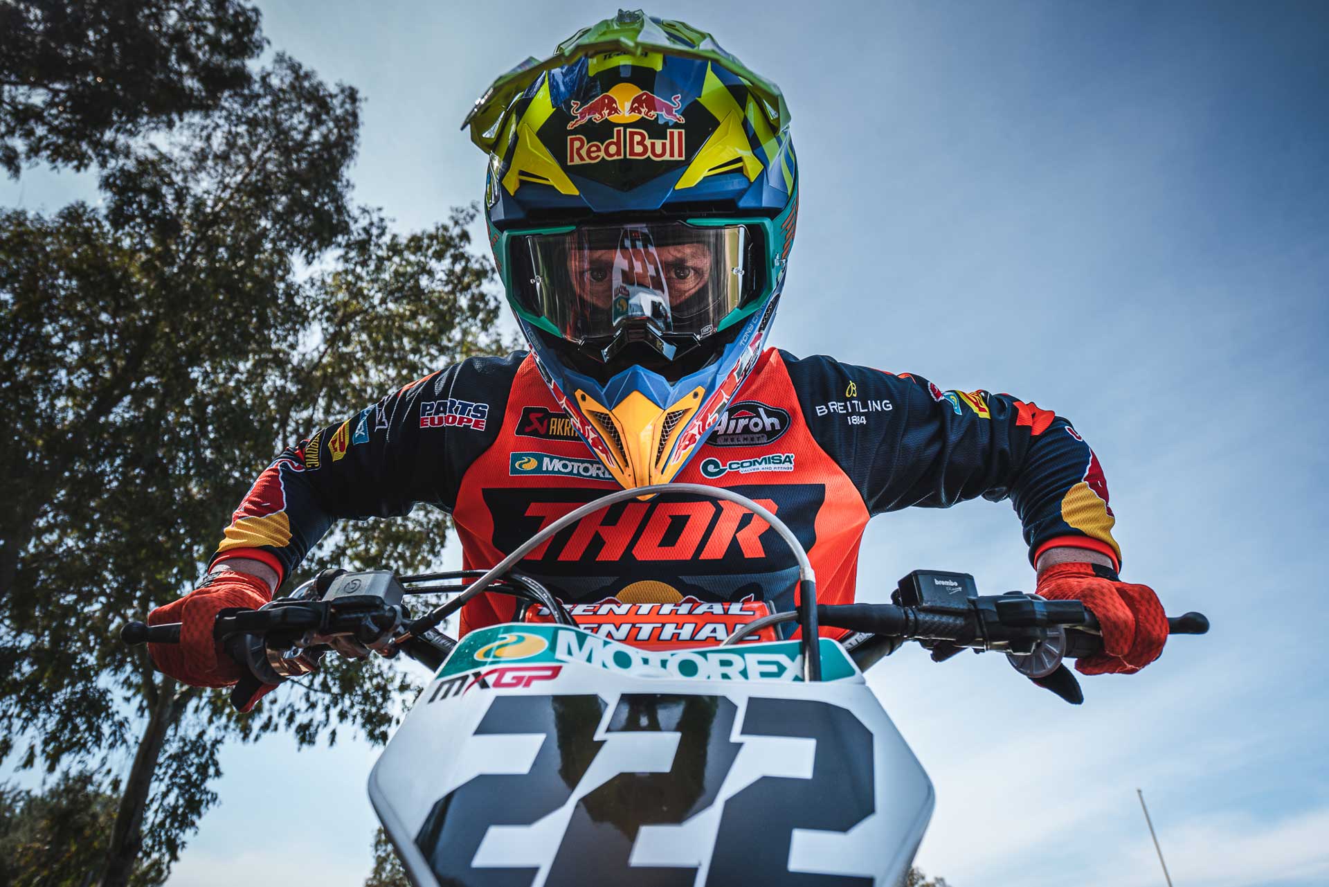 Motocross rider wearing a colorful Red Bull helmet and Thor gear with number 222 on the front of the bike.