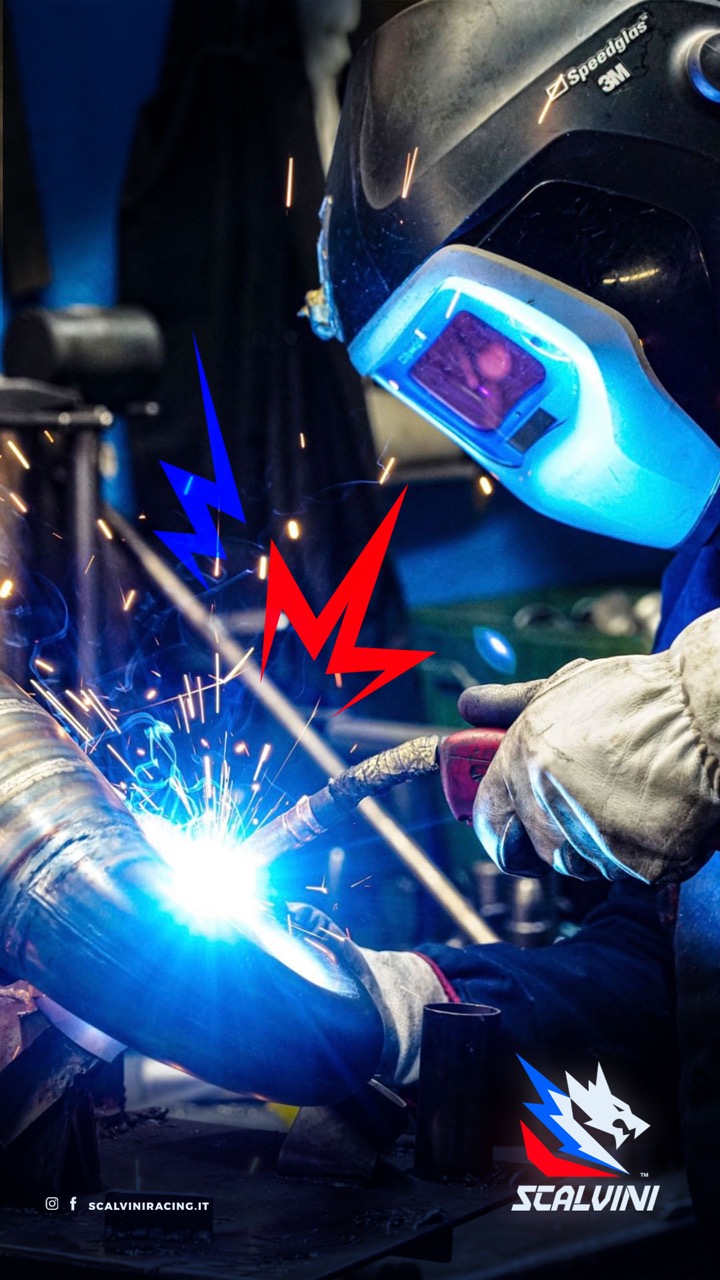 Person wearing a Speedglas 3M welding helmet and gloves welding a metal pipe, with sparks flying.
