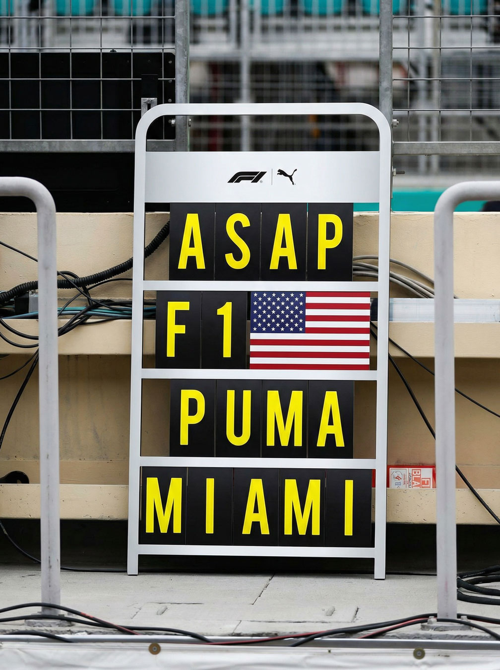 F1 pit board with yellow letters reading ASAP, F1 next to an American flag, PUMA, and MIAMI.
