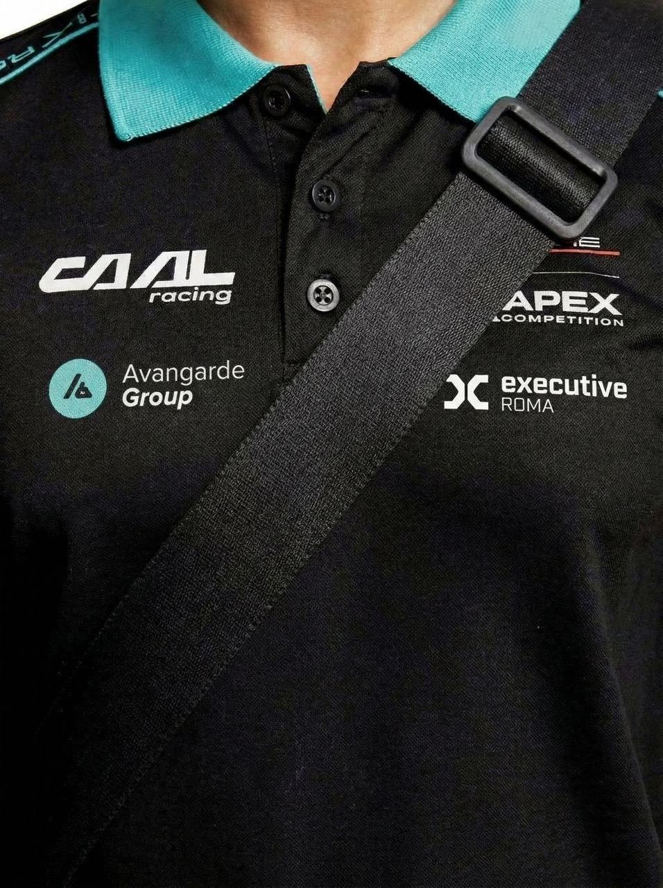 Close-up of a black polo shirt with a turquoise collar featuring logos: CAIL racing, Avangarde Group, APEX Competition, and executive ROMA, crossed by a black strap.