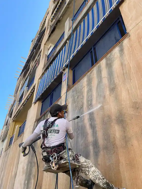 Hombre limpiando la fachada de un edificio