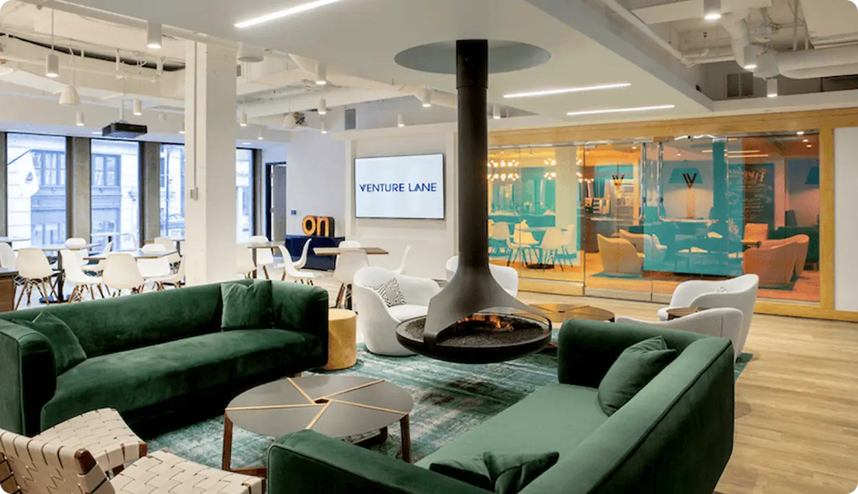 Espace coworking moderne avec cheminée suspendue et canapés en velours vert